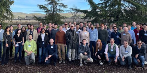 A photo outside with trees and large group of people